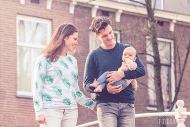 Fotoshoot met lieve peuter in Delft Een stel houdt een baby vast terwijl ze samen buiten wandelen.