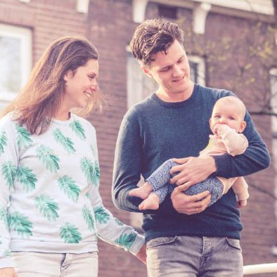 fotoshoot met baby in de binnenstad van Delft Een jong gezin wandelt samen in Delft; een vrouw en een man houden een baby vast.
