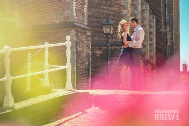 Gezinsfotoshoot in Delft Een stel omarmt elkaar op een zonnige locatie met kleurrijke bloemen op de voorgrond.