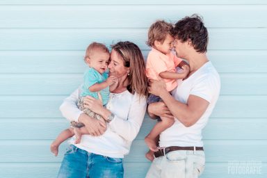 Fotoshoot bij een strandhuis in Hoek van Holland Gezin met twee jonge kinderen, blij tegen een lichte achtergrond.